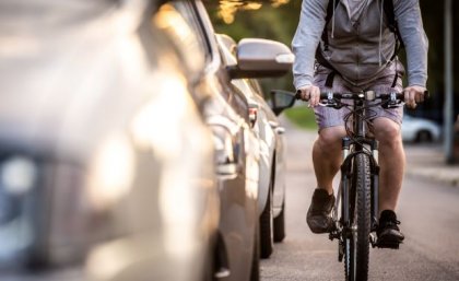 UQ research found Brisbane cyclists take longer and steeper routes to avoid traffic. Image: Adobe a cyclist riding close to a line of cars